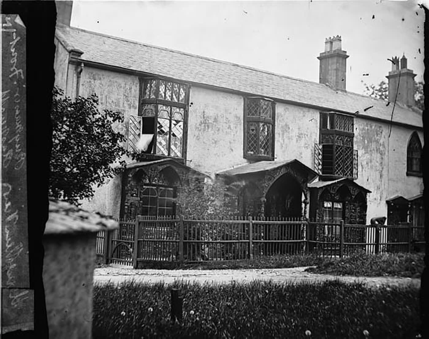 Plas Newydd, Llangollen, photographed in daylight with two Gothic windows and a wooden fence. The house after their deaths.